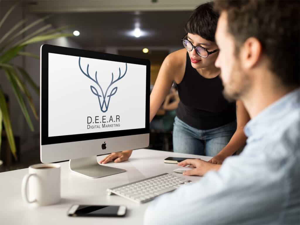 employees look at computer of D.E.E.A.R. Digital Marketing logo